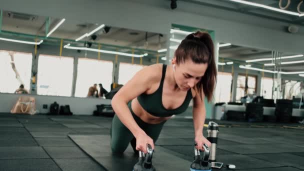 濃縮されたスポーツ女性は ジムで機器とヨガマットで演習を行っている — ストック動画