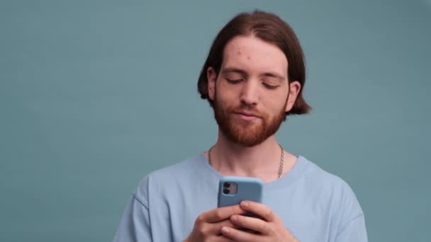 Stilig Man Använder Sin Smartphone Stående Isolerad Blå Färg Bakgrund — Stockvideo