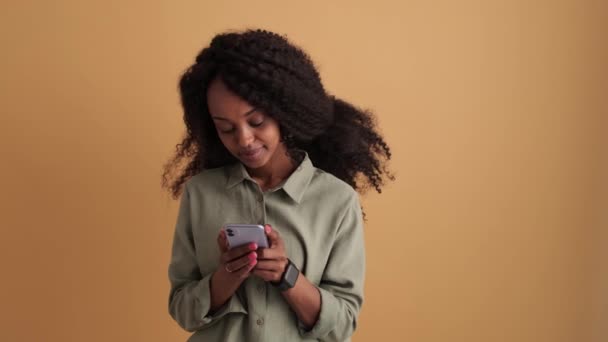 Una Joven Africana Sonriente Con Camisa Mirando Teléfono Estudio Naranja — Vídeos de Stock