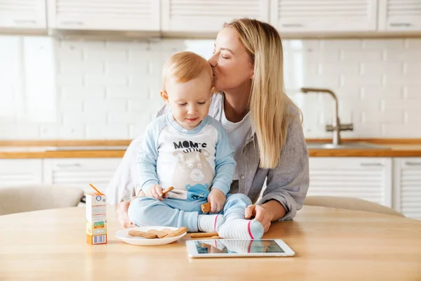 Feliz Hermosa Mujer Usando Tableta Mientras Besa Hijo Bebé Casa —  Fotos de Stock