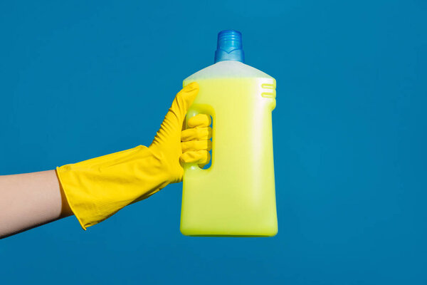 Closeup photo of hand wearing glove and cleaner isolated over blue wall