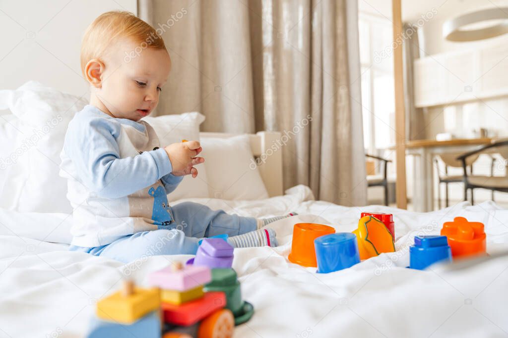 Happy smiling little baby boy playing on bed