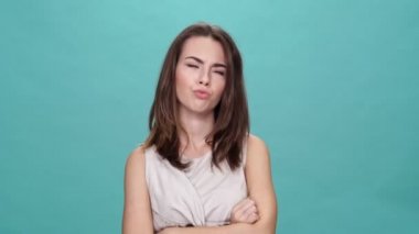 Çapraz kollu esmer kadın turkuaz arka planla ilgili bir şeye katılmıyor.