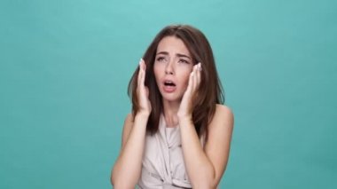 Tişörtlü hasta esmer kadın turkuaz arka planda hapşırıyor.