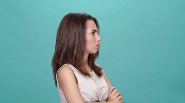 Tişörtlü, turkuaz arka planda çapraz kollu esmer bir kadını gücendirdi.