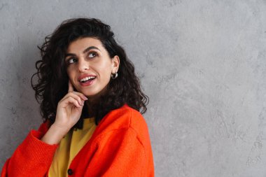 Mutlu güzel esmer kız gülümsüyor ve yukarı bakıyor gri duvarın üzerinde.
