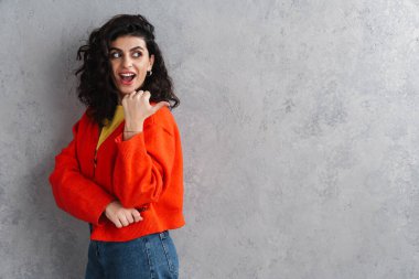 Mutlu gülümseyen güzel genç bir kadın gri arka planda izole edilmiş bir telif alanı gösteriyor.