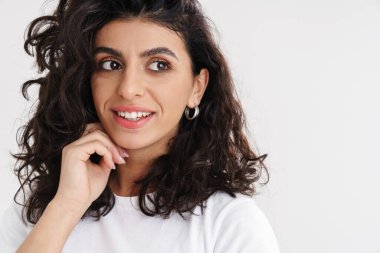 Mutlu güzel esmer kız gülümsüyor ve beyaz arka planda soyutlanmış bir şekilde yan tarafa bakıyor.