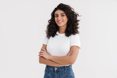 Mutlu güzel esmer kız kollarını kavuşturup beyaz arka planda yalnız poz veriyor.