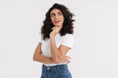 Heyecanlı güzel esmer kız gülümsüyor ve beyaz arka planda tek başına bir kenara bakıyor.