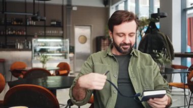 Memnun bir adam kafede oturmuş notlar alıyor.