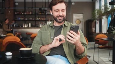 Pozitif bir adam kafede oturup kahve içerken video bağlantısıyla konuşuyor.