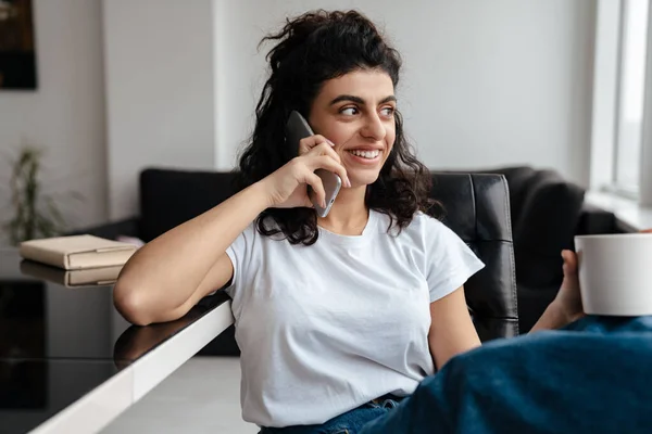 Smiling Brunette Woman Talking Mobile Phone While Drinking Coffee Home — Stock Photo, Image