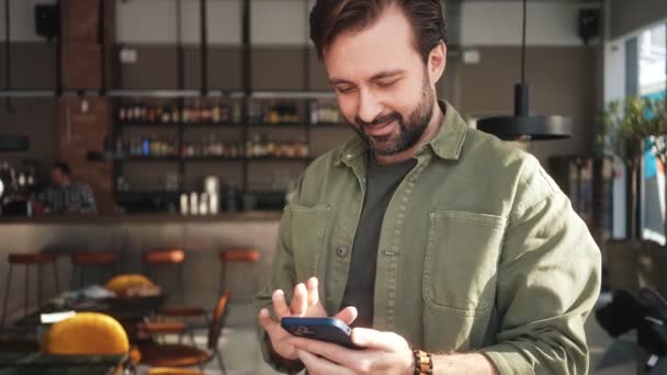 Hombre Guapo Está Usando Teléfono Inteligente Mientras Está Pie Café — Vídeo de stock