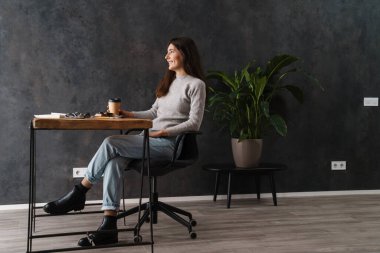 Gülümseyen güzel kaligraf kız, masa içinde çalışırken kahve içiyor.