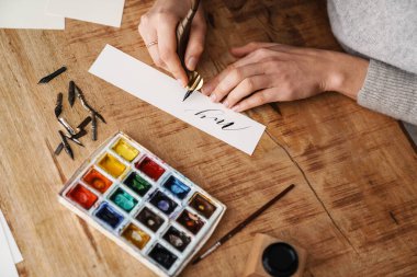 Hattat kız içeride çalışırken yazı yazıyor.