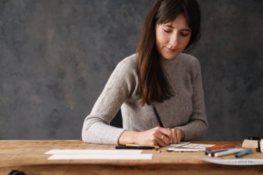 Kapalı bir masada çalışırken yazı yazan çok güzel bir kaligraf kız.
