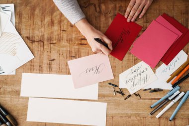 Kapalı bir masada sevgililer günü kartı üzerinde çalışırken kaligraf kız yazı yazıyor.