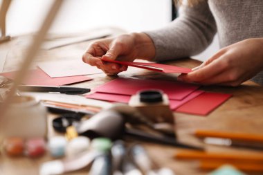 Kaligraf kız kapalı bir masada sevgililer günü kartı üzerinde çalışıyor.