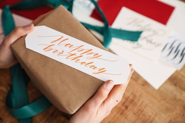 Hattat kız kapalı bir masada doğum günü hediyesi üzerinde çalışıyor.