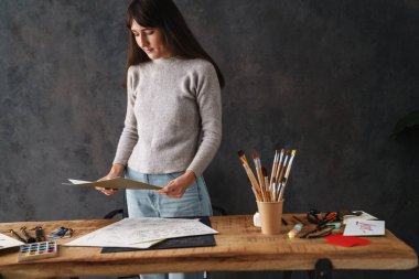 Odaklanmış güzel kaligraf kız kapalı bir masada çizimlerle çalışıyor.