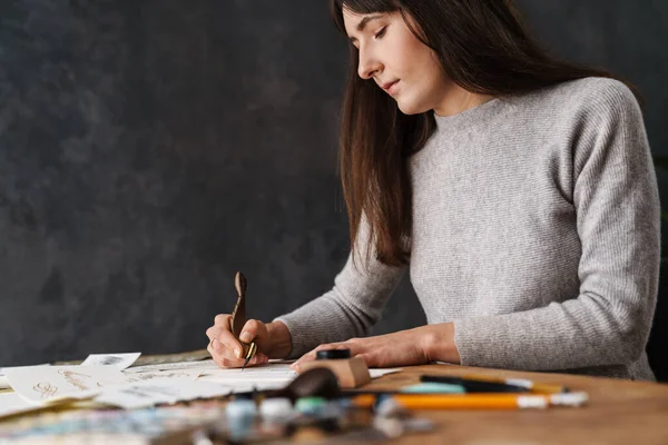 Kapalı bir masada çalışırken yazı yazan çok güzel bir kaligraf kız.