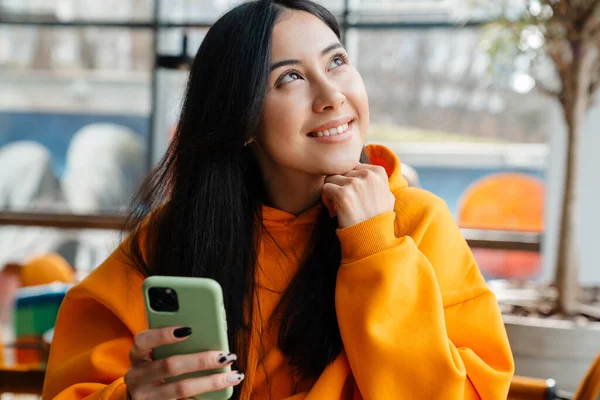 Kafede Otururken Cep Telefonu Kullanan Gülümseyen Asyalı Kadın — Stok fotoğraf