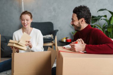 Çekici genç çift yeni bir eve taşınıyor, bavullarını boşaltıyor.