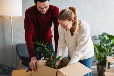 Çekici mutlu genç çift yeni bir eve taşınıyor, bavullarını boşaltıyor.
