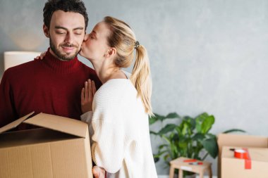Yeni bir evde birlikte hareket eden gülümseyen bir çiftin portresi.
