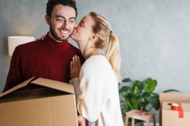 Yeni bir evde birlikte hareket eden gülümseyen bir çiftin portresi.