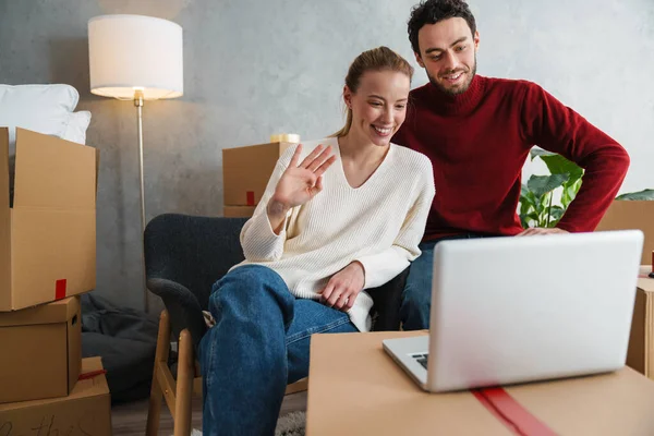 Casal Sorridente Com Laptop Sentado Chão Casa Nova Acenando Mãos — Fotografia de Stock