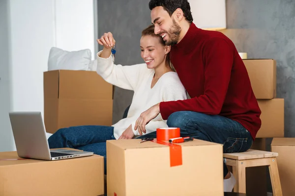 Pareja Sonriente Con Portátil Sentado Suelo Una Casa Nueva Mostrando —  Fotos de Stock