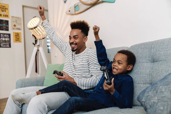 Emocionado Afroamericano Padre Hijo Haciendo Gesto Ganador Mientras Juega Videojuego —  Fotos de Stock