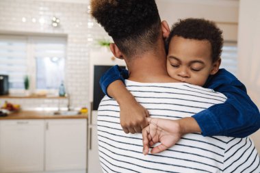 Baba, oğlunu mutfakta taşırken yakın çekim.
