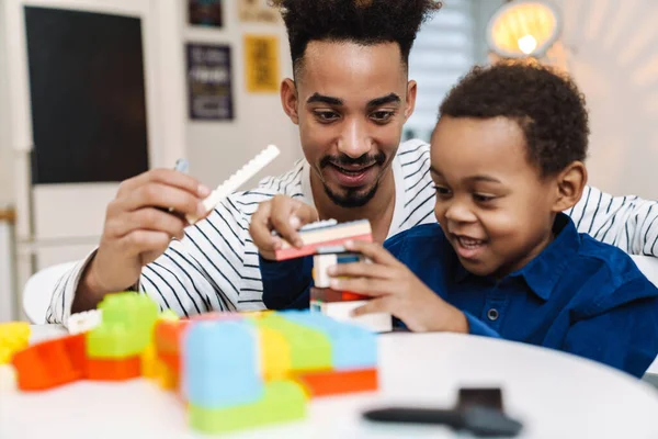 Mutlu Afrikalı Amerikalı çocuk evde gülümseyen babasıyla oynuyor.