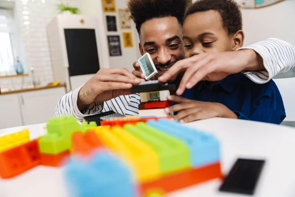 Mutlu Afrikalı Amerikalı çocuk evde gülümseyen babasıyla oynuyor.