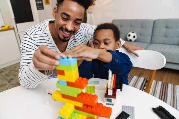 Mutlu Afrikalı Amerikalı çocuk evde gülümseyen babasıyla oynuyor.