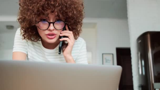 Gözlüklü Üzgün Kıvırcık Saçlı Kızın Evde Dizüstü Bilgisayara Bakarken Telefonda — Stok video