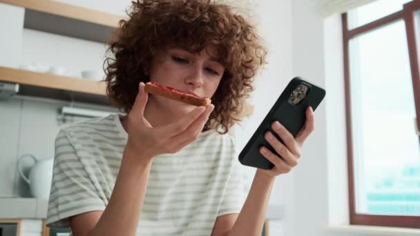 Una Vista Cerca Chica Pelo Rizado Mirando Teléfono Comiendo Tostadas — Vídeo de stock