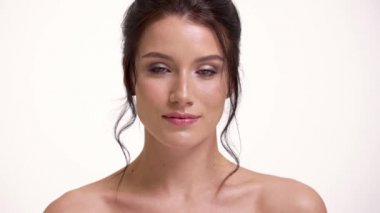 Pozitif yarı çıplak bir kadının yakın çekimi stüdyodaki beyaz duvarın üzerinde izole bir şekilde duran kameraya bakıyor.