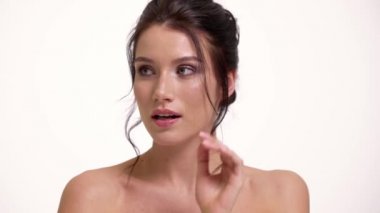 Hayal gören mutlu yarı çıplak bir kadının yakın çekimi stüdyodaki beyaz duvarın üzerinde tek başına duran kameraya bakıyor.