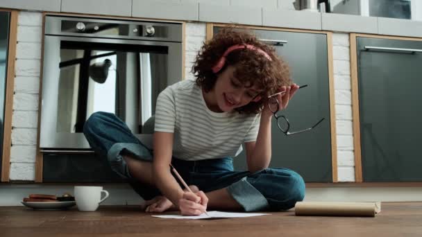 Een Vrolijk Krullend Meisje Koptelefoon Die Iets Tekent Terwijl Vloer — Stockvideo