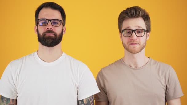 Två Positiva Killar Med Glasögon Nickar Till Kameran Stående Isolerad — Stockvideo