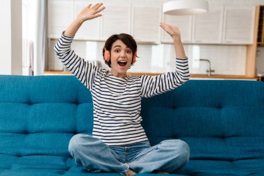 Heyecanlı kız evdeki koltukta kulaklıkla müzik dinlerken eğleniyor.