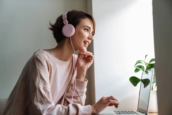 Glückliche Schöne Mädchen Mit Kopfhörern Arbeiten Mit Laptop Fenster Drinnen — Stockfoto