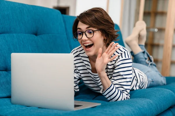 Izgatott Szép Használja Laptop Integető Kéz Miközben Feküdt Kanapén Otthon — Stock Fotó