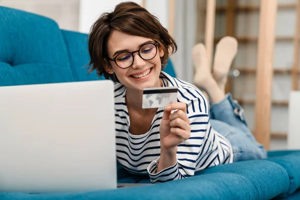 Mulher Bonita Feliz Óculos Usando Cartão Crédito Laptop Sofá Casa — Fotografia de Stock