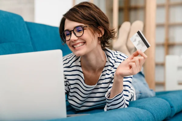 Mulher Bonita Feliz Óculos Usando Cartão Crédito Laptop Sofá Casa — Fotografia de Stock