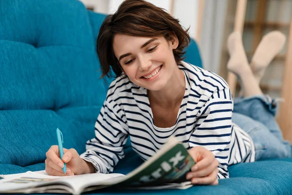 Feliz Chica Hermosa Estudiante Haciendo Tarea Mientras Está Acostado Sofá —  Fotos de Stock